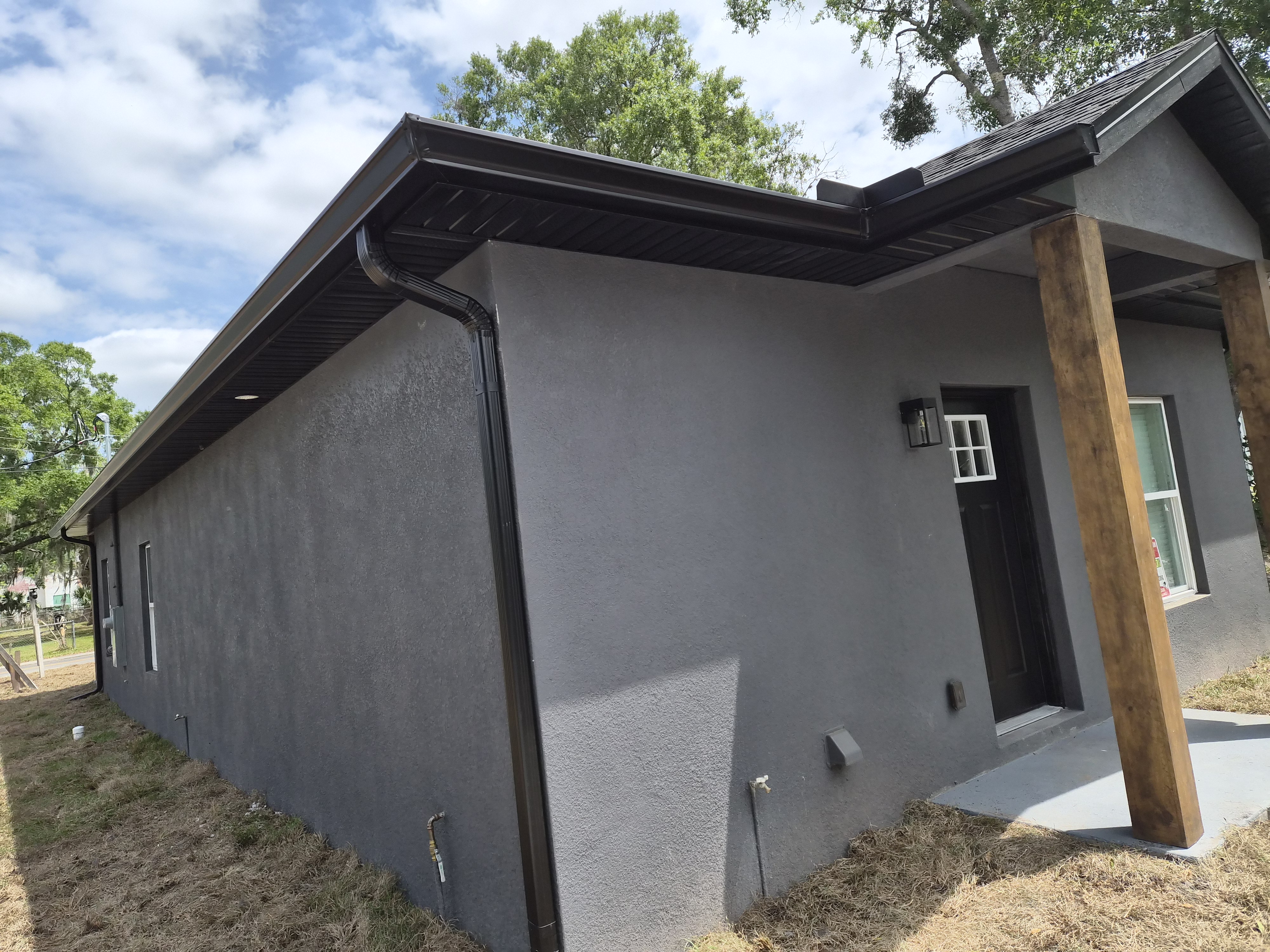 Dark bronze 7-inch seamless gutters with downspout installed on a modern home by M12 Gutters