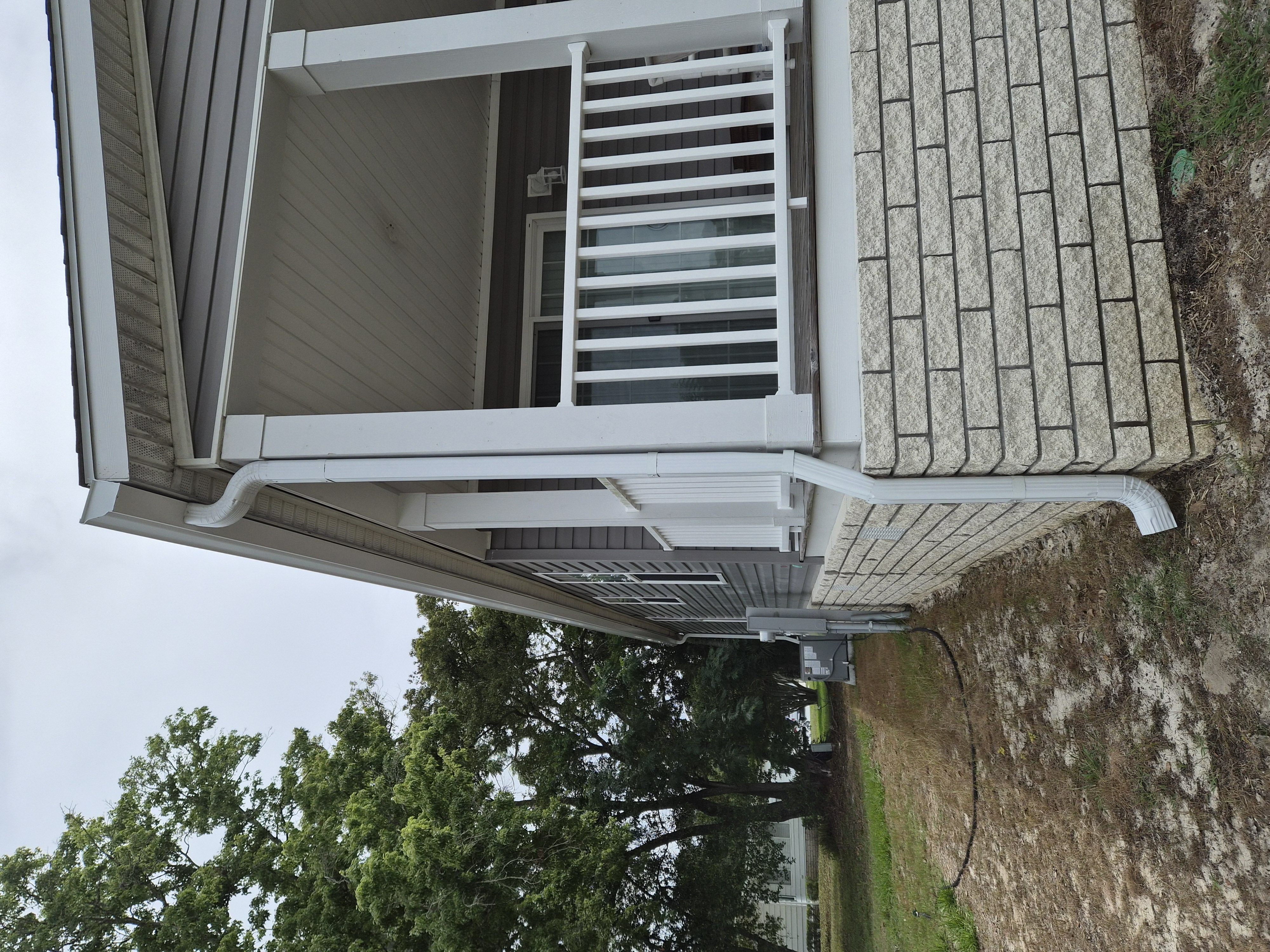 Home exterior showing white gutters and downspouts by M12 Gutters